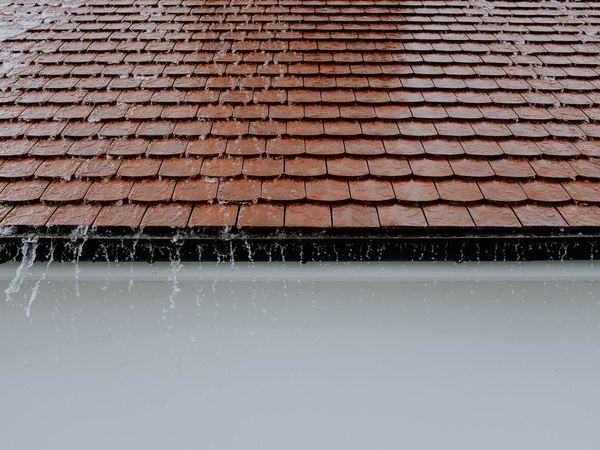 Rain running off the edge of a terracotta tiled roof